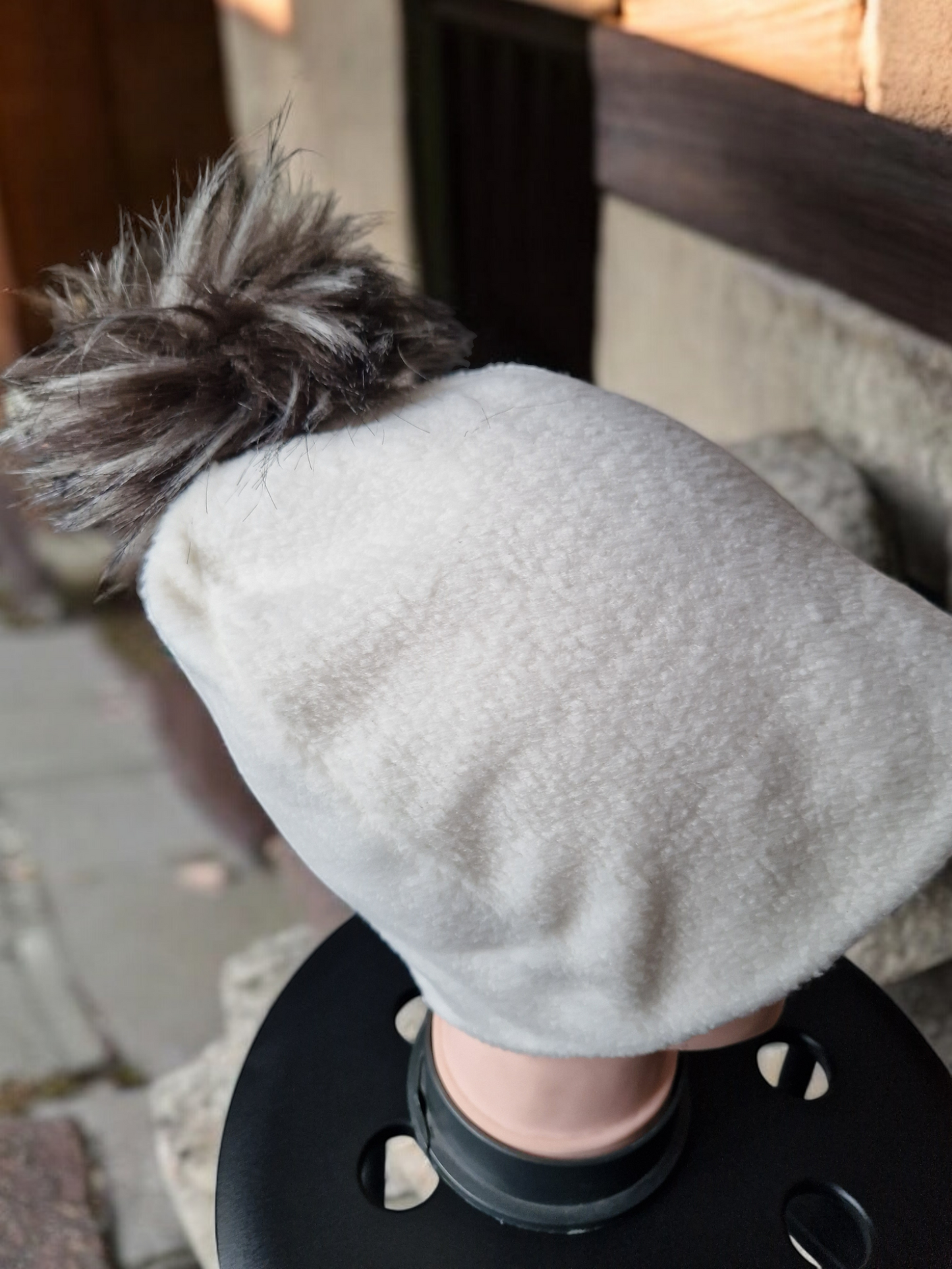 Cream women's fleece hat with brown/cream fur pompom.