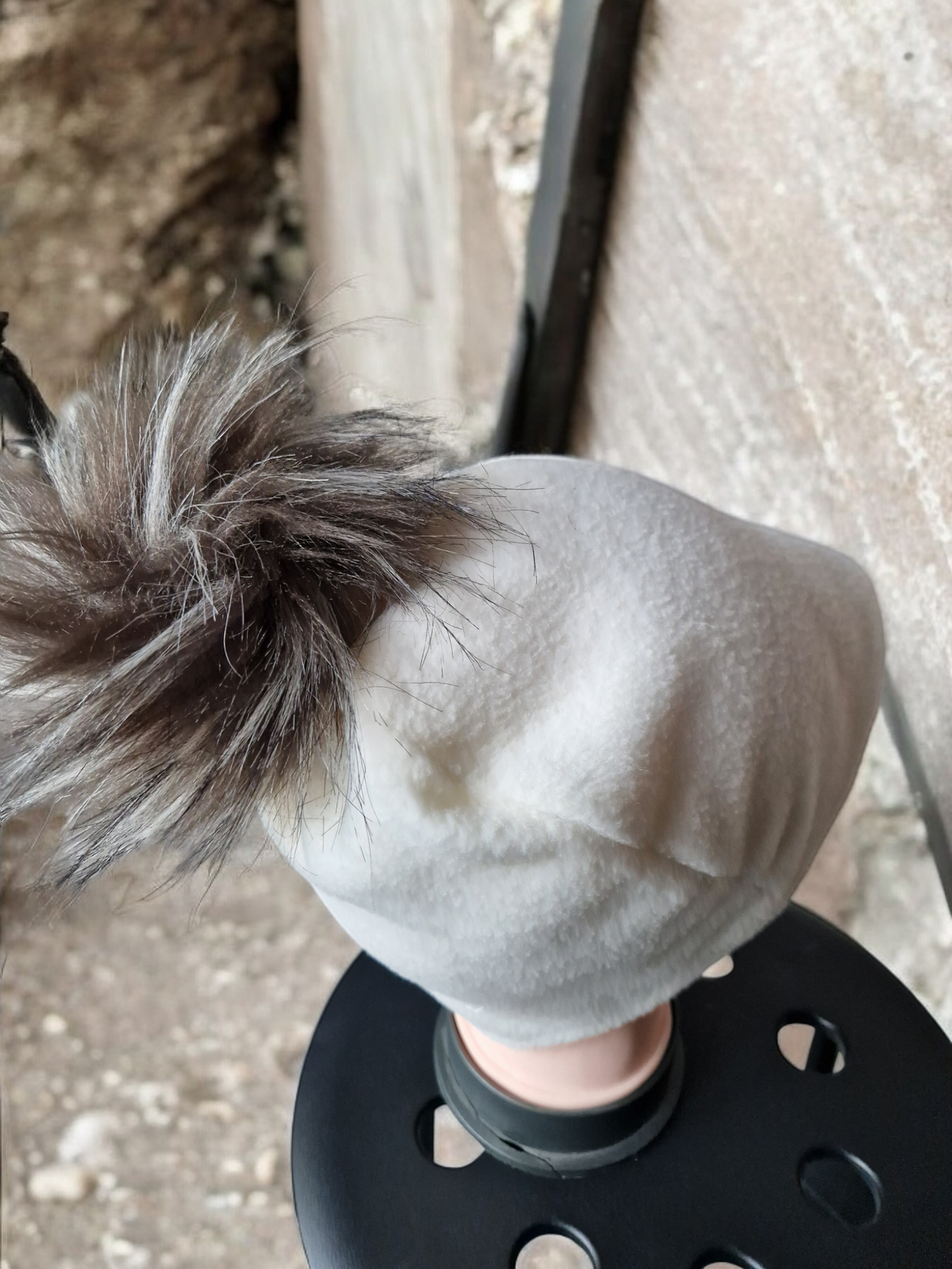 Cream women's fleece hat with brown/cream fur pompom.