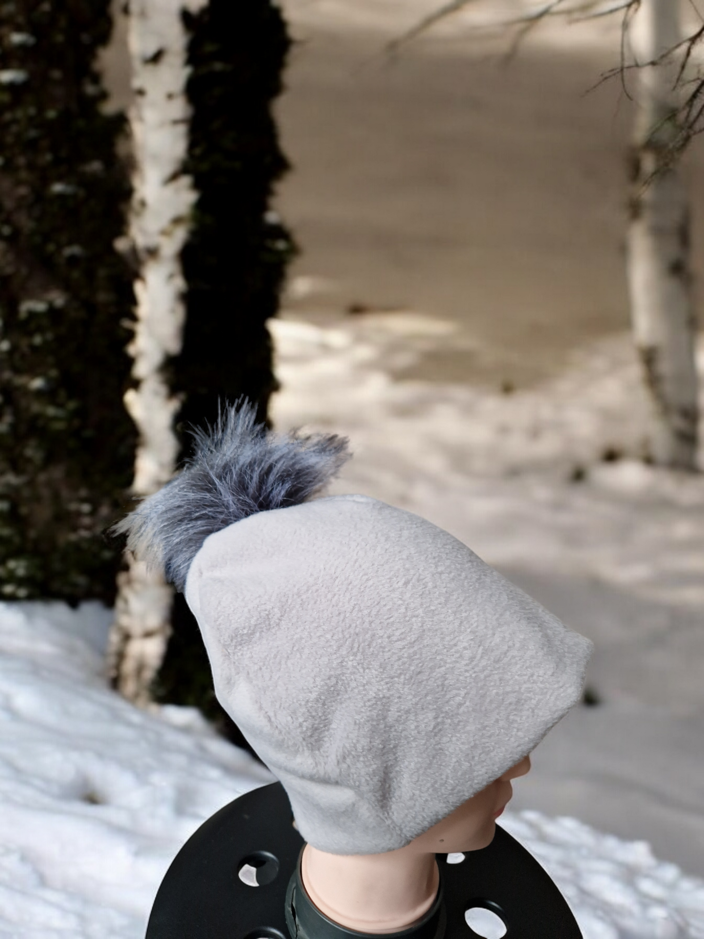 Light grey women's fleece hat with grey fur pompom.