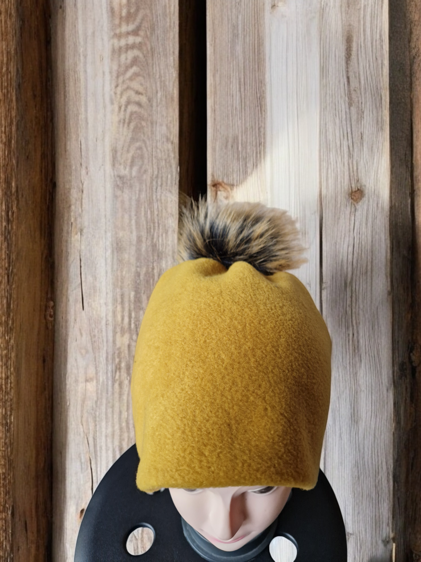 Mustard women's fleece hat with brown fur pompom.