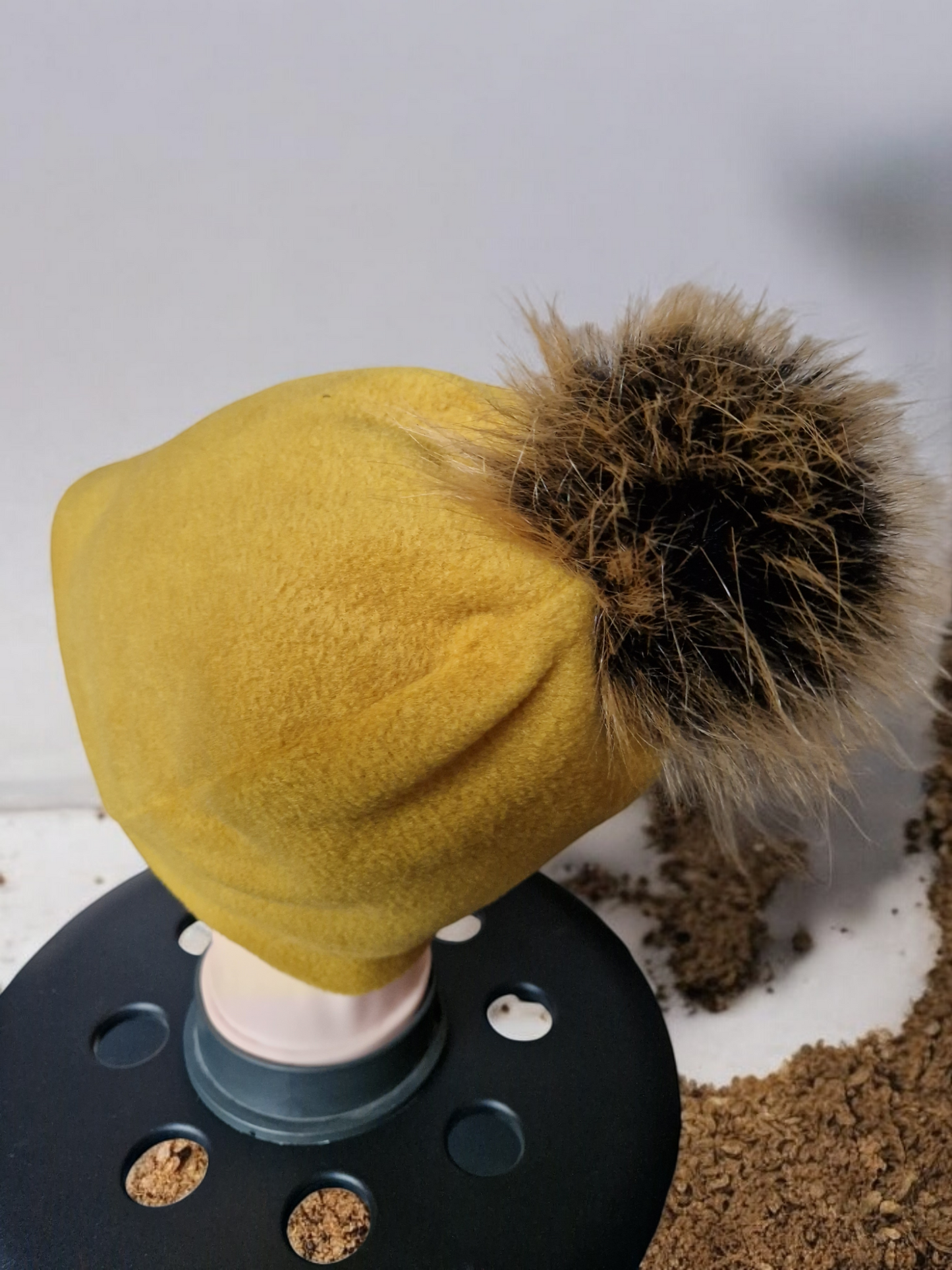 Mustard women's fleece hat with brown fur pompom.