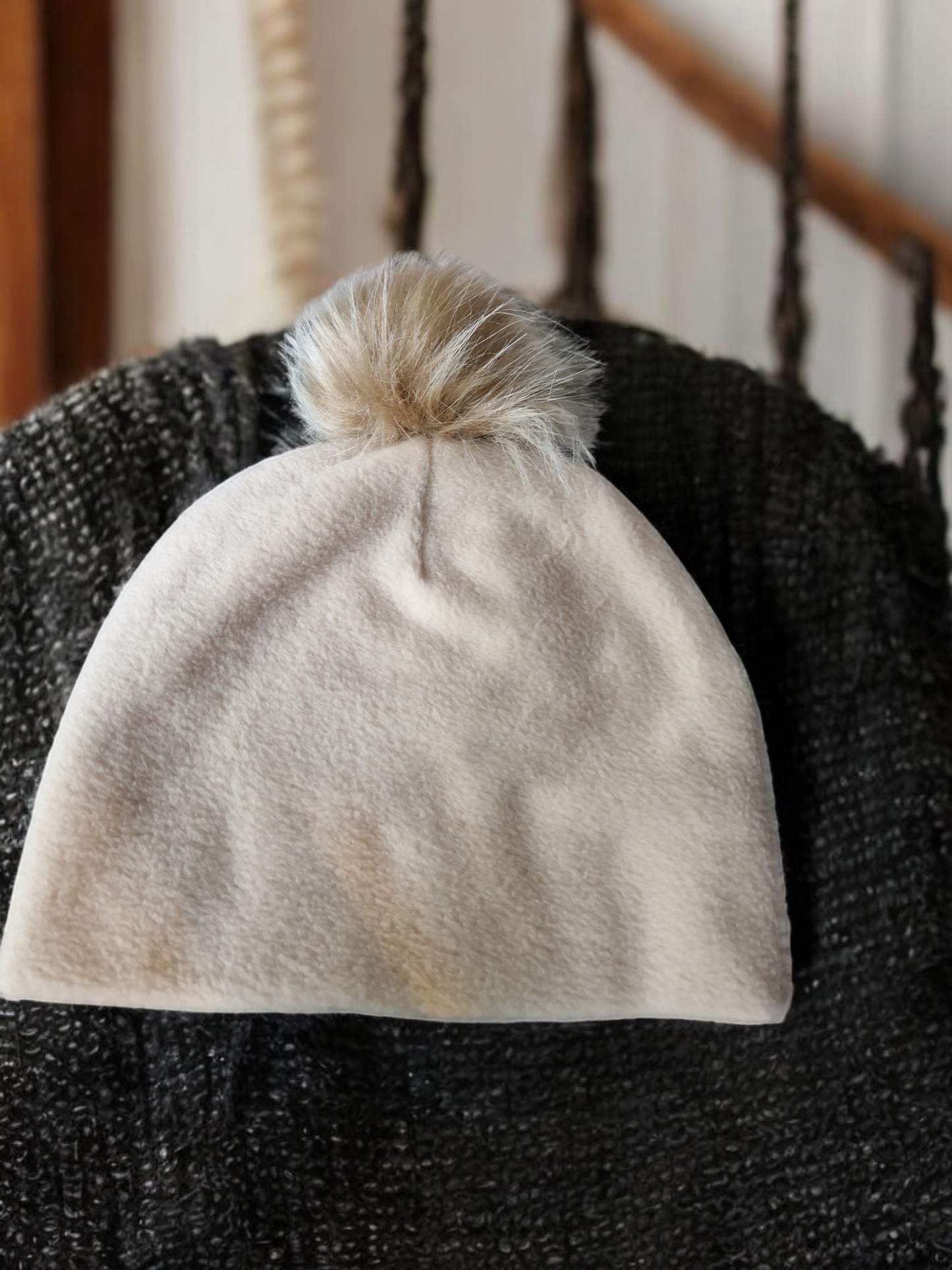 Cream beige women's fleece hat with carmel fur pompom.